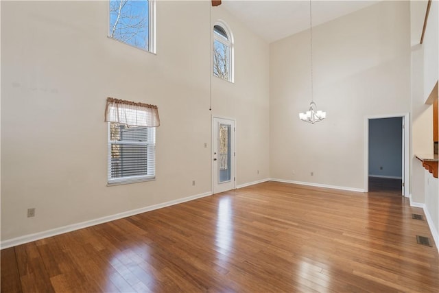 unfurnished living room featuring light wood finished floors, visible vents, baseboards, and a notable chandelier