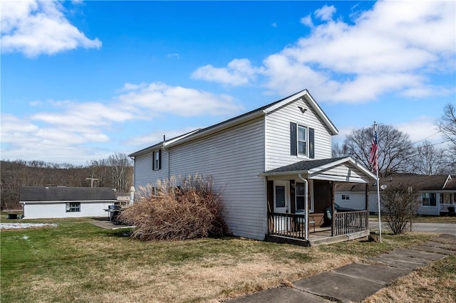 traditional home with a front yard, covered porch, and an outdoor structure