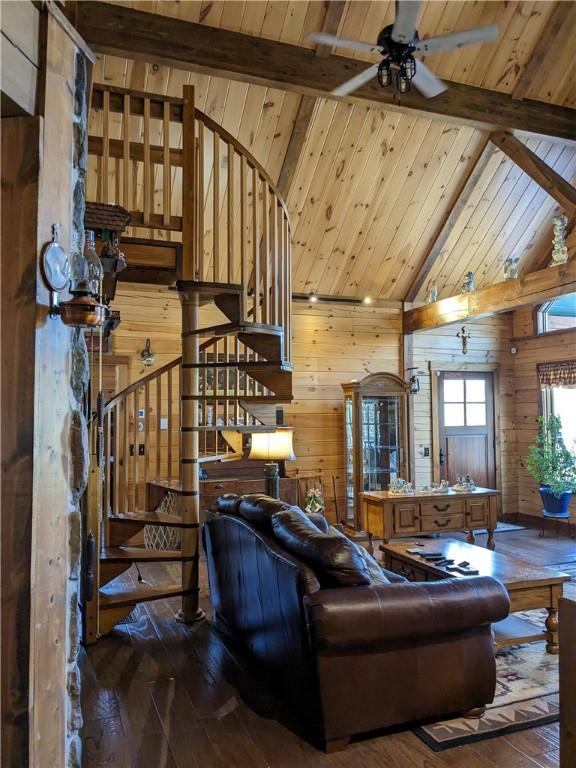 living room with wooden ceiling, wood walls, beamed ceiling, and wood finished floors