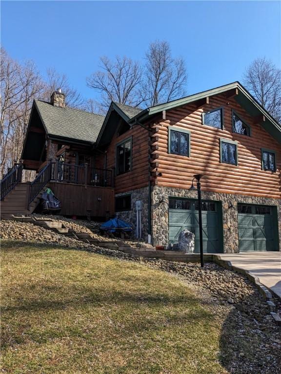 view of side of home featuring concrete driveway, a chimney, log siding, an attached garage, and stairs