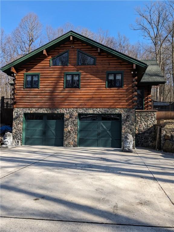 view of side of property featuring a garage, log siding, and concrete driveway