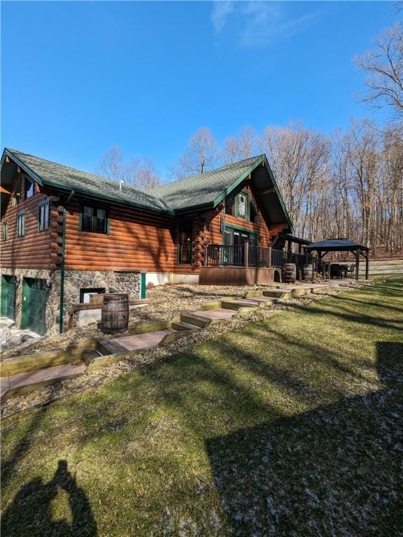 back of property featuring stone siding, a lawn, a deck, and log siding