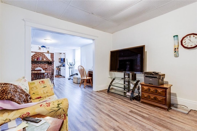 living area featuring wood finished floors, a paneled ceiling, and baseboards