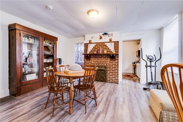 dining room with a drop ceiling, a wealth of natural light, and light wood-style floors