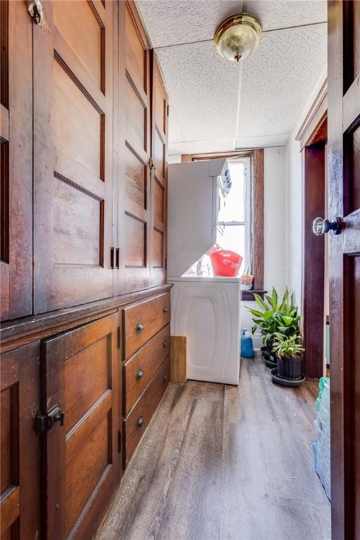 interior space featuring a textured ceiling, laundry area, and wood finished floors