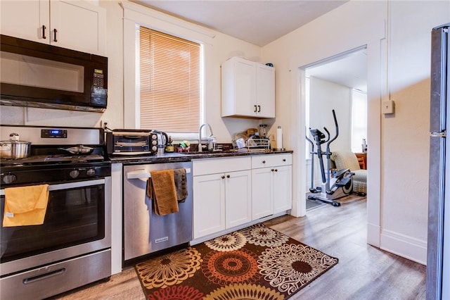 kitchen featuring a sink, appliances with stainless steel finishes, light wood-style floors, and white cabinets