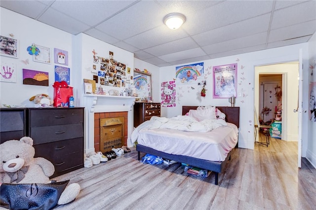 bedroom featuring light wood-type flooring and a drop ceiling