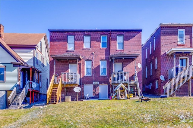 back of house with a yard, stairs, and brick siding