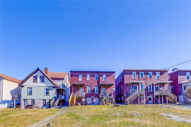 exterior space with stairs, a lawn, a chimney, and a residential view