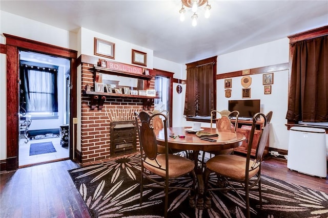 dining space featuring a brick fireplace, baseboards, and wood finished floors