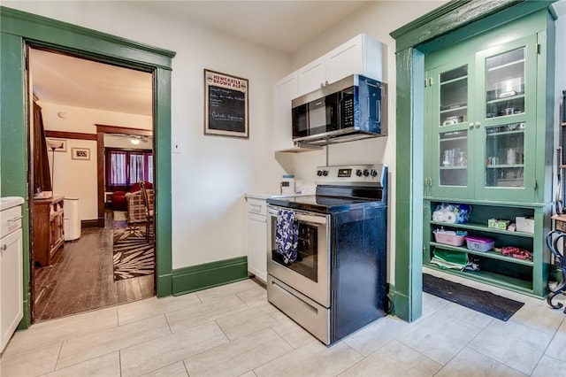 kitchen featuring white cabinets, ceiling fan, baseboards, and stainless steel appliances