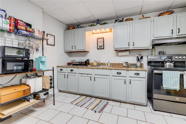 kitchen featuring black microwave, a paneled ceiling, under cabinet range hood, a sink, and stainless steel range with electric stovetop