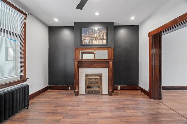 unfurnished living room with radiator, baseboards, wood finished floors, and recessed lighting