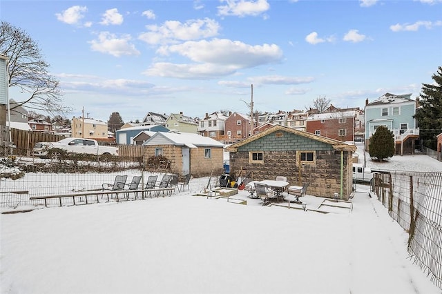 snow covered rear of property featuring fence and a residential view