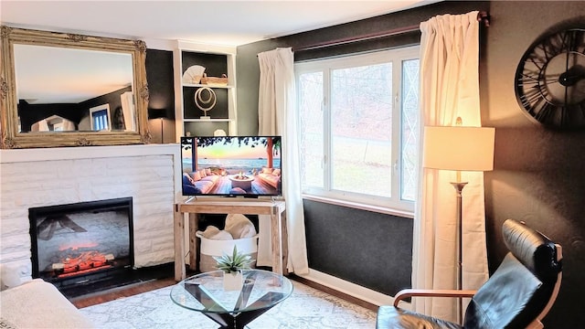 living area featuring a fireplace, wood finished floors, and baseboards
