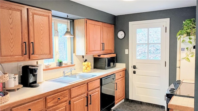 kitchen with black dishwasher, tile counters, hanging light fixtures, decorative backsplash, and a sink