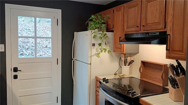 kitchen with light countertops, electric range, brown cabinets, and under cabinet range hood