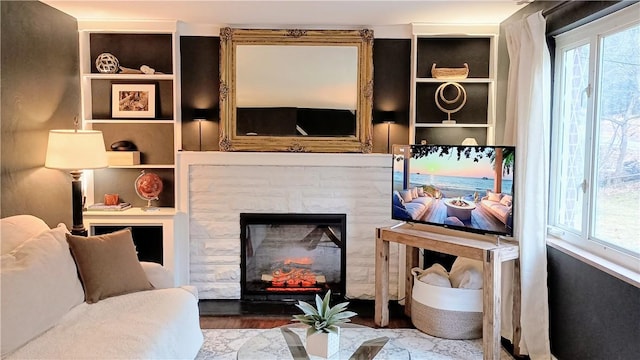 living room featuring a stone fireplace and wood finished floors