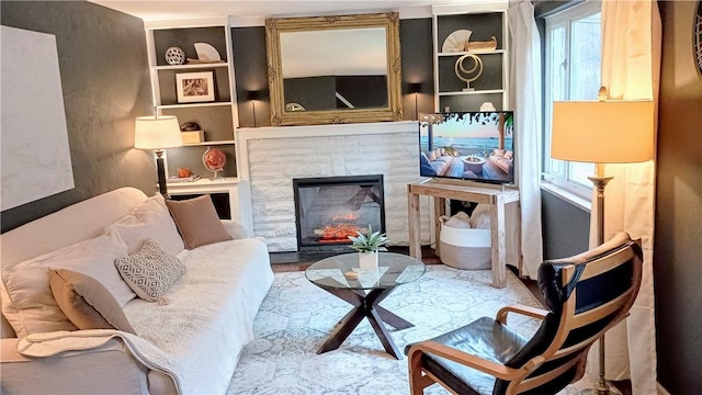 living area with a stone fireplace and wood finished floors