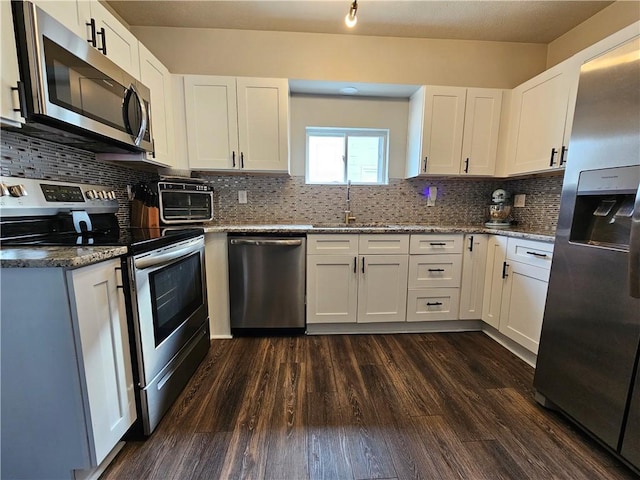 kitchen featuring appliances with stainless steel finishes, white cabinets, a sink, and light stone counters