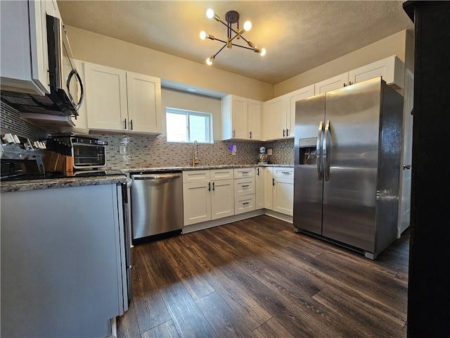 kitchen featuring a sink, white cabinets, appliances with stainless steel finishes, backsplash, and dark wood-style floors