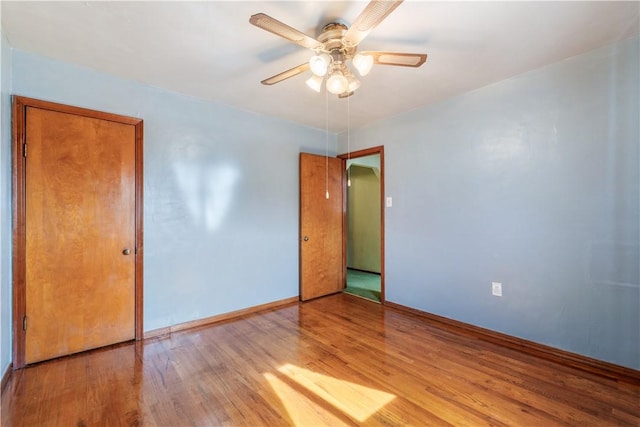 empty room featuring light wood-type flooring, baseboards, and a ceiling fan