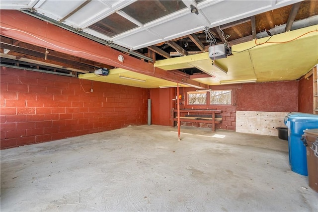 garage featuring concrete block wall and a garage door opener