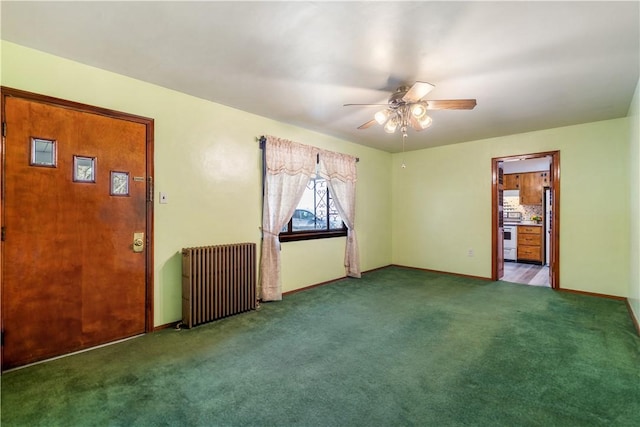 carpeted empty room featuring baseboards, a ceiling fan, and radiator