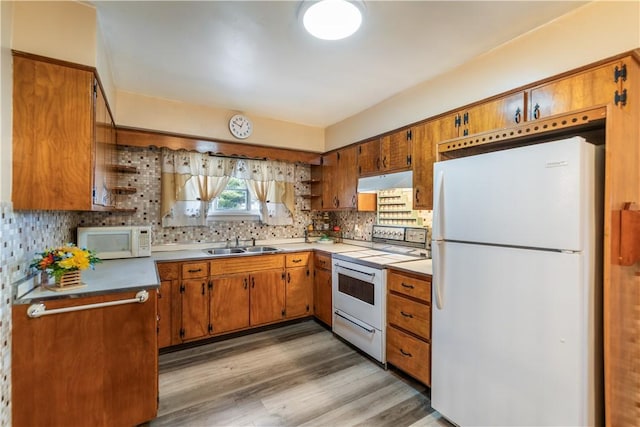 kitchen with white appliances, light countertops, a sink, and under cabinet range hood