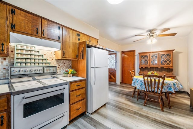 kitchen featuring under cabinet range hood, light countertops, freestanding refrigerator, range, and tasteful backsplash