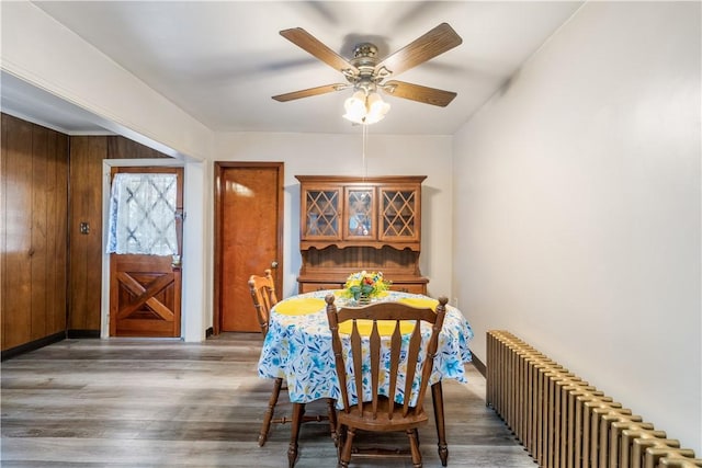 dining area featuring ceiling fan, dark wood-type flooring, and radiator