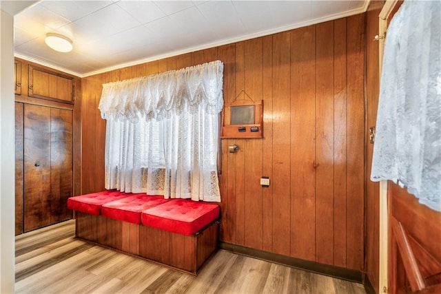 bedroom with light wood-style floors, crown molding, and wood walls