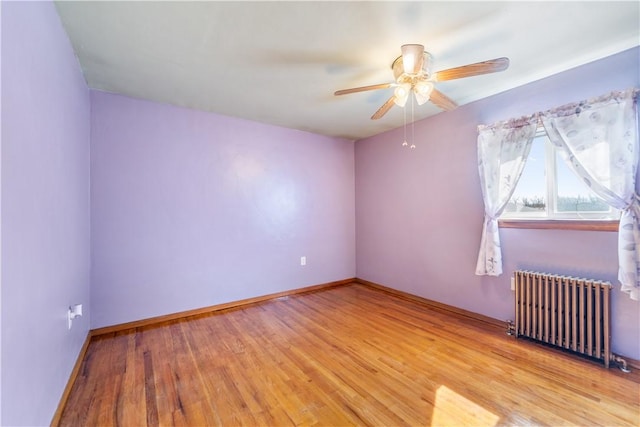 unfurnished room with baseboards, ceiling fan, radiator heating unit, and light wood-style floors