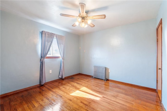 unfurnished room featuring baseboards, radiator heating unit, a ceiling fan, and light wood-style floors