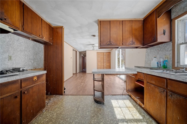 kitchen with light countertops, brown cabinetry, backsplash, and light floors