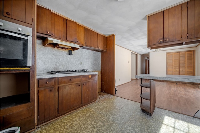 kitchen featuring light countertops, light floors, gas cooktop, and brown cabinets