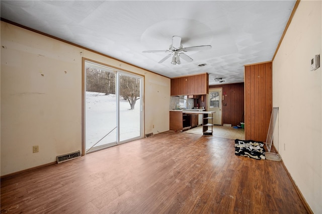 unfurnished living room with crown molding, visible vents, light wood-style floors, ceiling fan, and baseboards