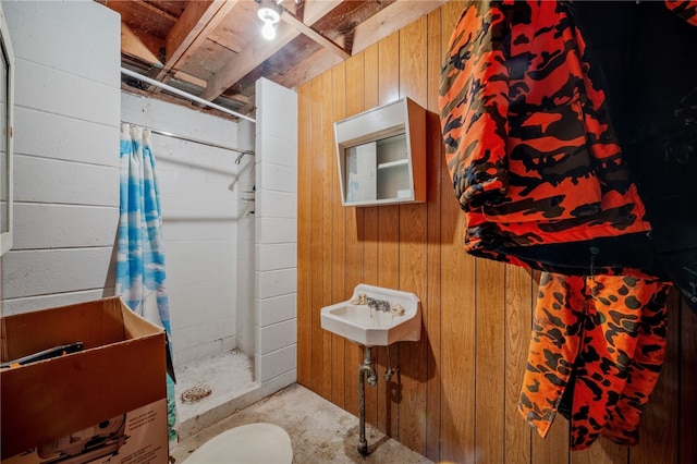 bathroom featuring concrete flooring, wooden walls, and a walk in shower