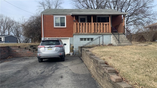 view of front of home featuring a garage, covered porch, brick siding, driveway, and a front lawn