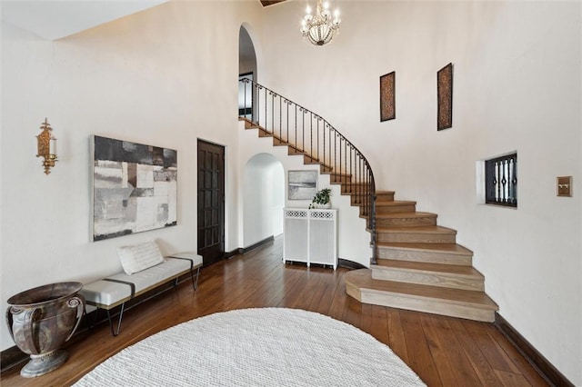 entryway featuring stairs, dark wood-type flooring, arched walkways, and baseboards