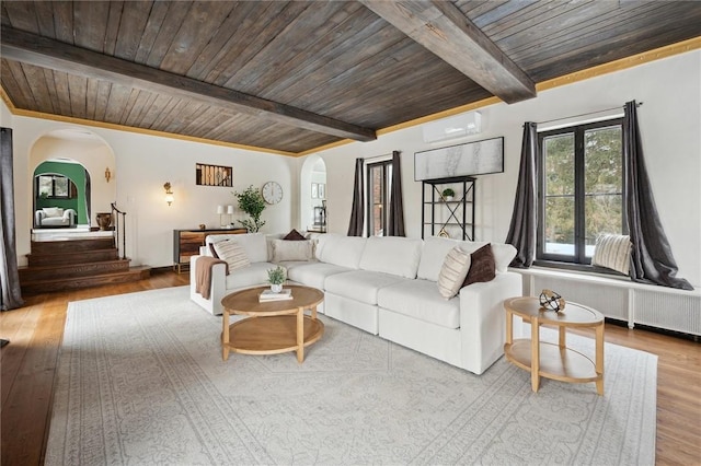 living area featuring arched walkways, a wall mounted air conditioner, wood ceiling, and radiator