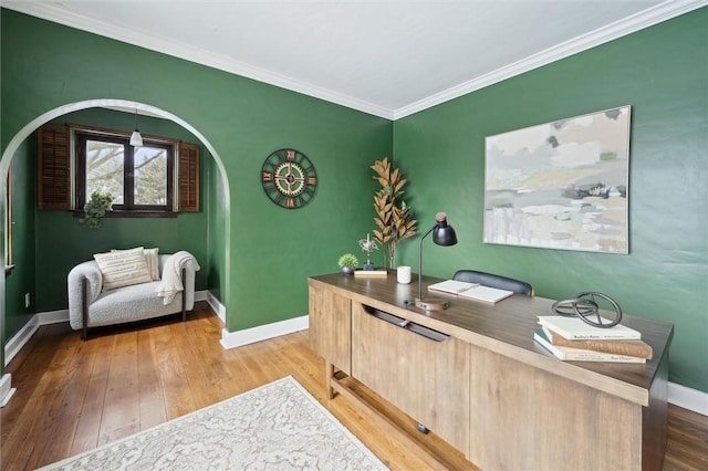 home office with arched walkways, crown molding, baseboards, and wood finished floors