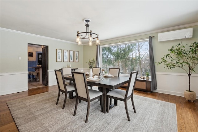 dining room with baseboards, ornamental molding, wood finished floors, an inviting chandelier, and a wall mounted AC