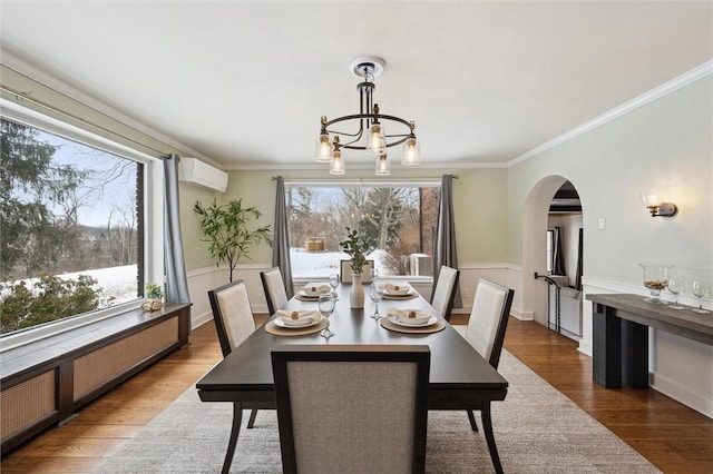 dining space with a wainscoted wall, a wall mounted air conditioner, crown molding, and wood finished floors