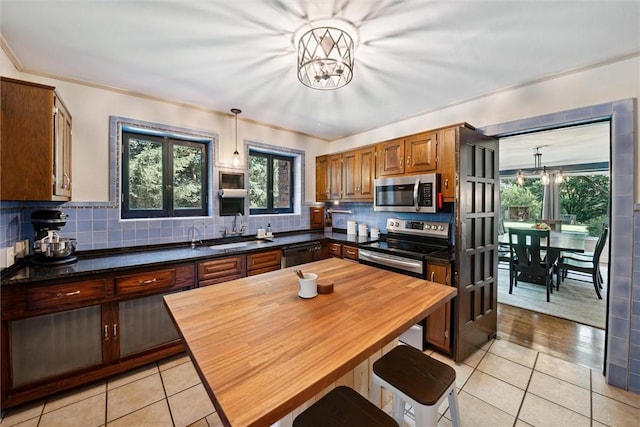 kitchen with stainless steel appliances, dark countertops, a notable chandelier, and hanging light fixtures