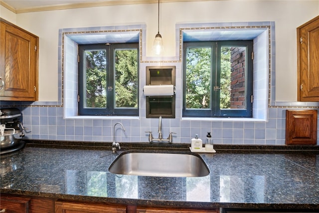 kitchen with tasteful backsplash, a healthy amount of sunlight, brown cabinets, and hanging light fixtures