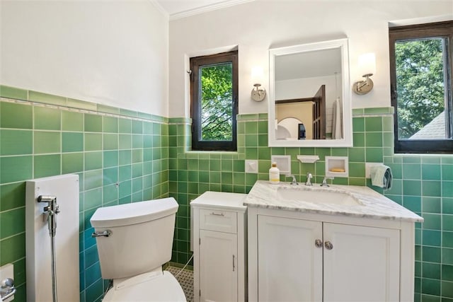 bathroom with toilet, vanity, a wealth of natural light, and tile walls