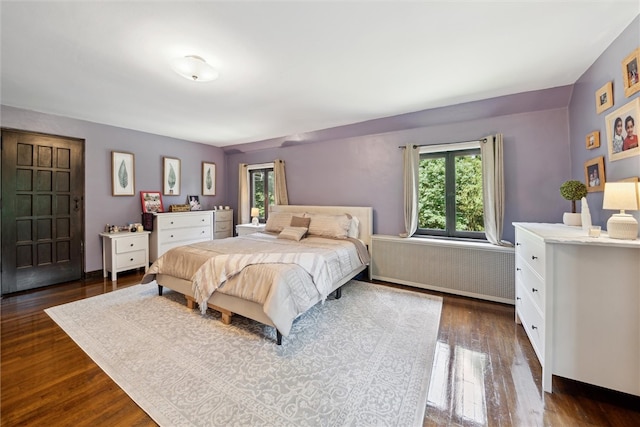 bedroom featuring radiator heating unit, multiple windows, and dark wood finished floors