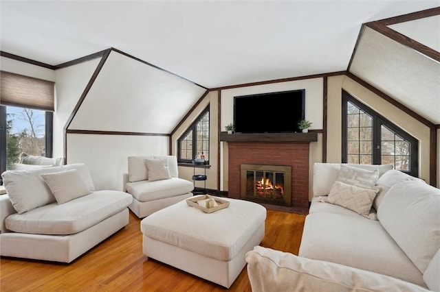 living area featuring crown molding, a fireplace, vaulted ceiling, and wood finished floors