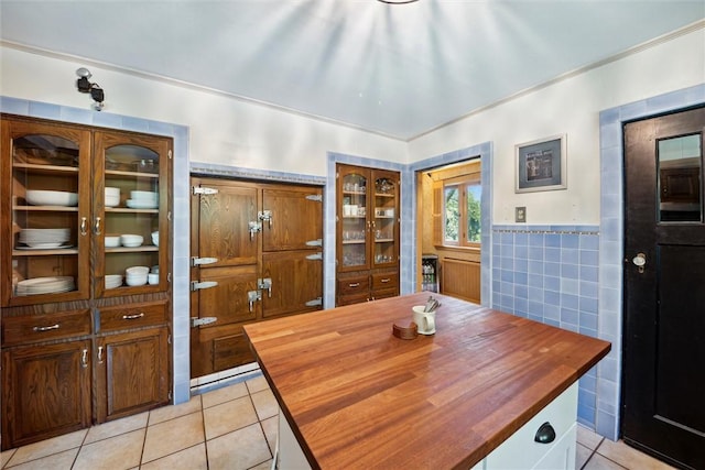 dining space with a wainscoted wall, light tile patterned flooring, and tile walls